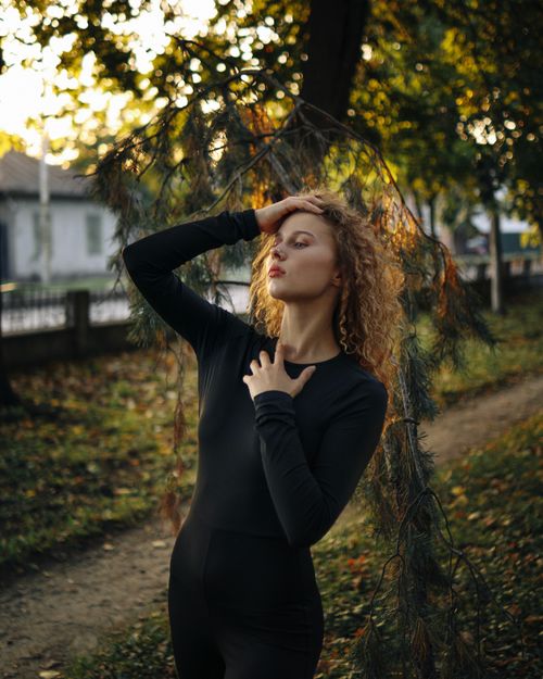 Free Stylish woman in black posing among autumn trees, exuding elegance and allure. Stock Photo