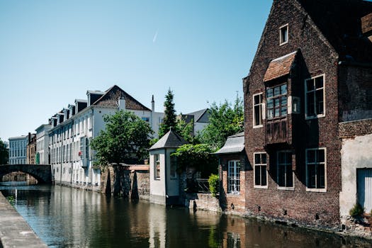 Picturesque view of a canal surrounded by historic buildings and a bridge in Bruges, Belgium.