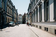 Cobblestone street in Bruges lined with historic townhouses under a bright day.