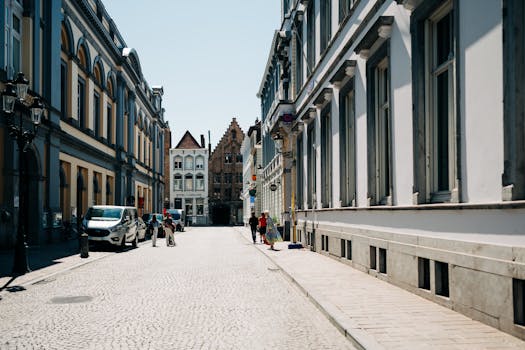 Cobblestone street in Bruges lined with historic townhouses under a bright day.