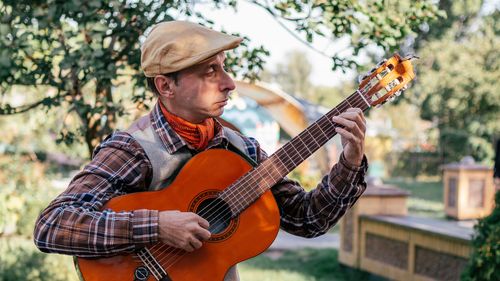 Free Man in a park enjoying music with an acoustic guitar on a sunny day. Stock Photo