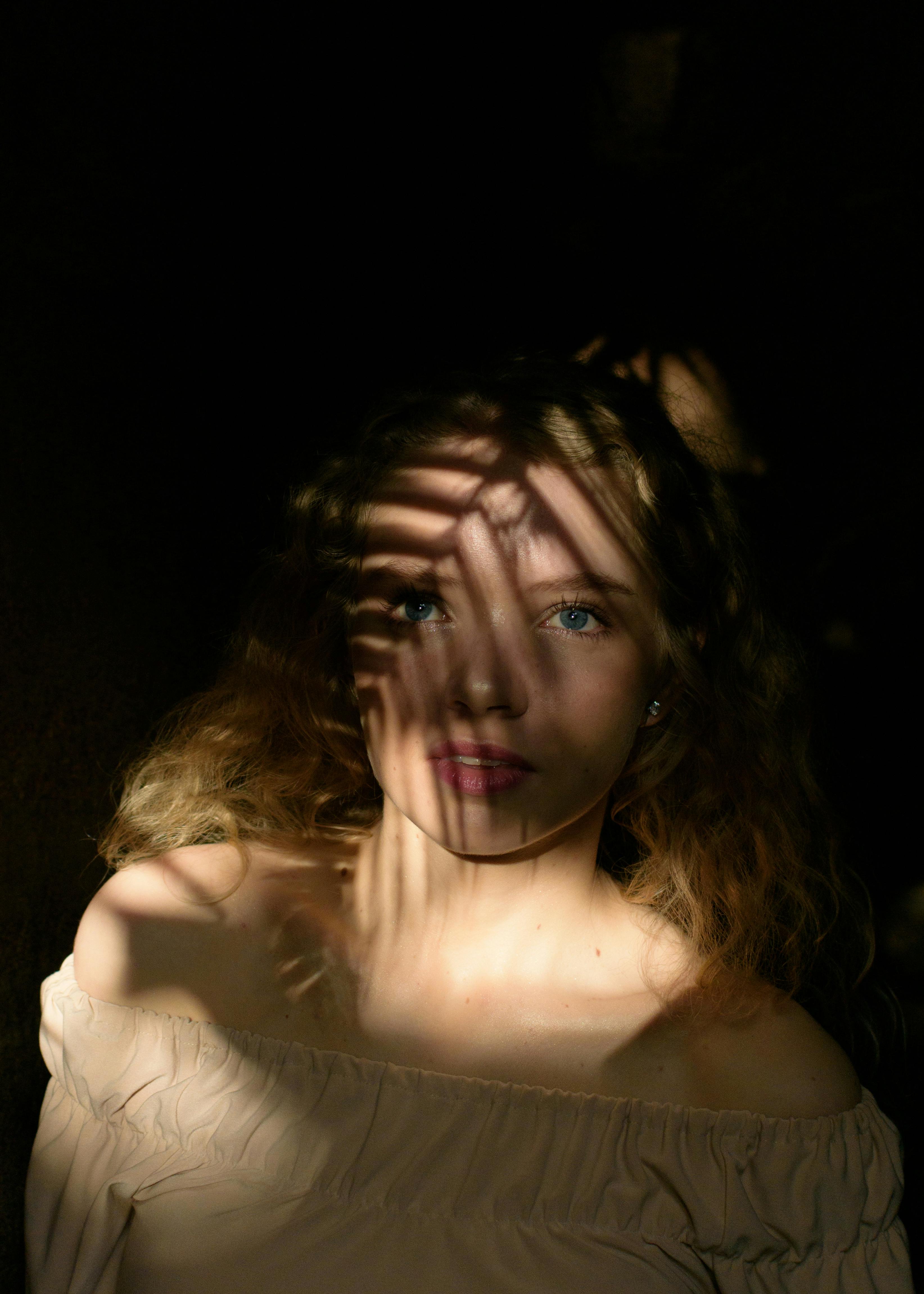 A young woman with shadow patterns across her face, creating an artistic and dramatic portrait.
