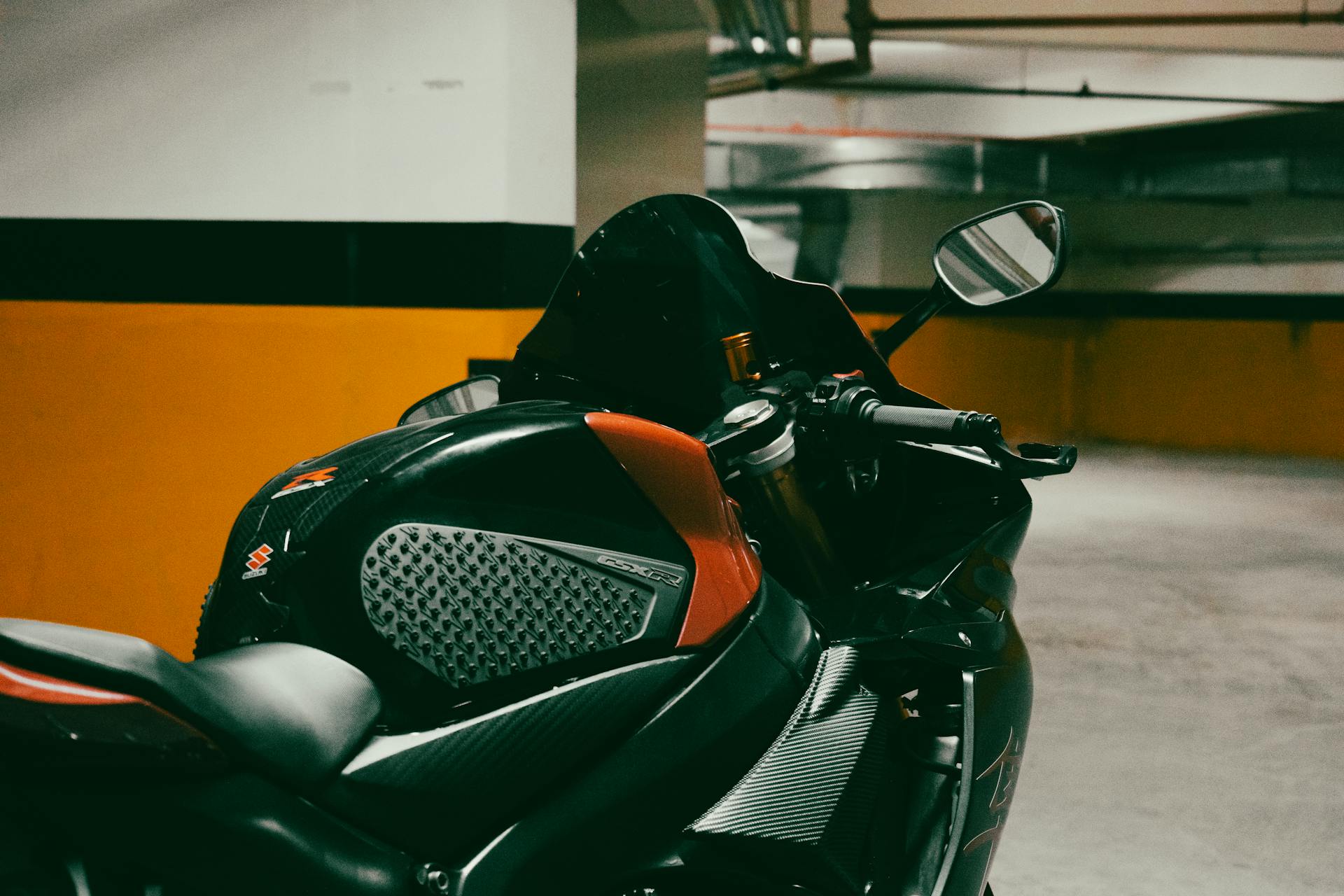 A detailed view of a sleek motorcycle parked in an underground garage with dramatic lighting.