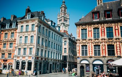 Maisons ornées et beffroi sur la Grand Place de Lille par une journée ensoleillée, mettant en valeur les monuments locaux.