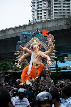 Crowd celebrating Ganesh Chaturthi with a giant Ganesha idol on a street in Mumbai, India.
