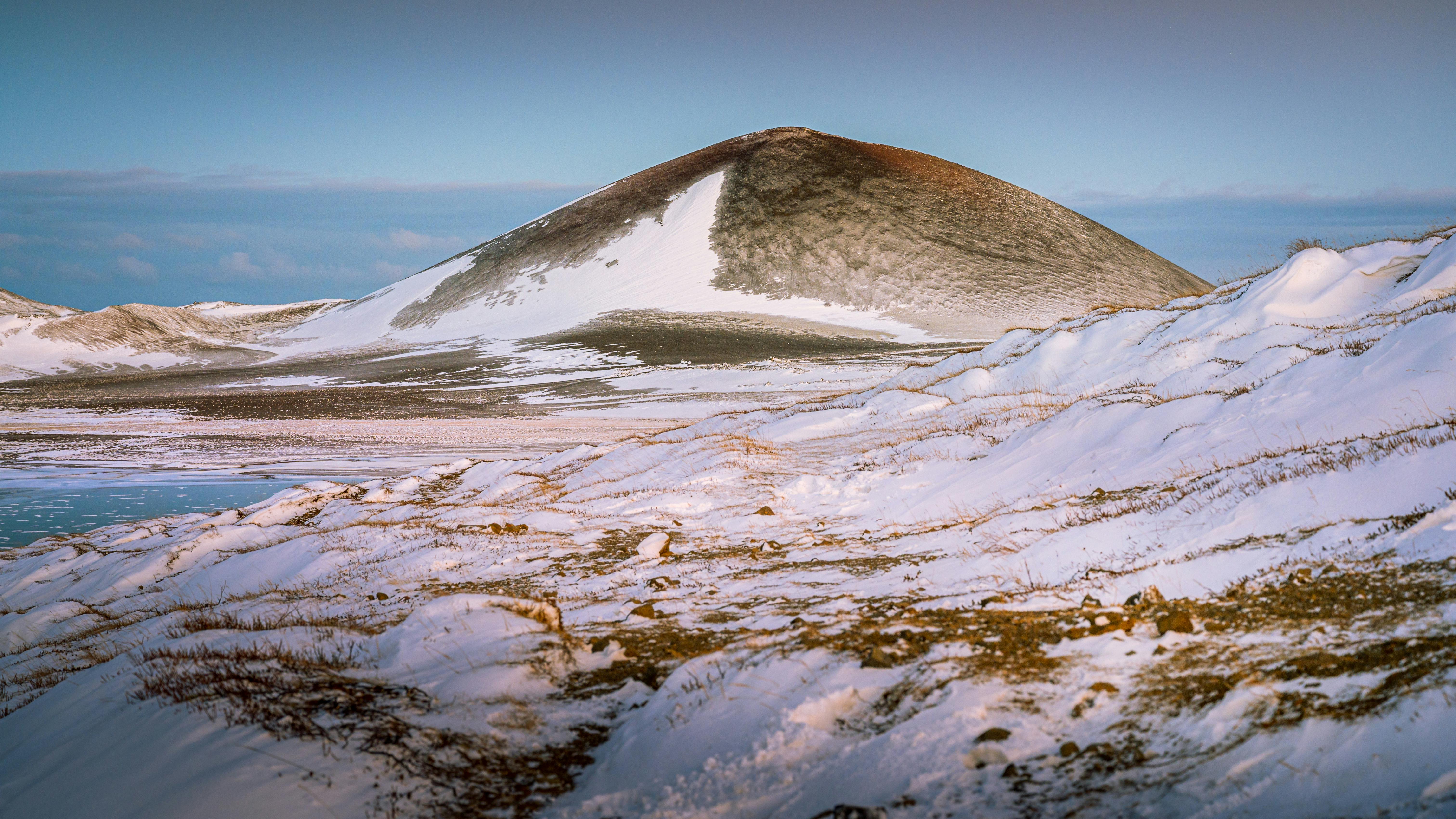 Scenic winter landscape of a snowy hill and icy terrain in Stykkishólmur, Iceland.