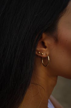 Stylish close-up of a woman's ear adorned with gold hoop and stud earrings.