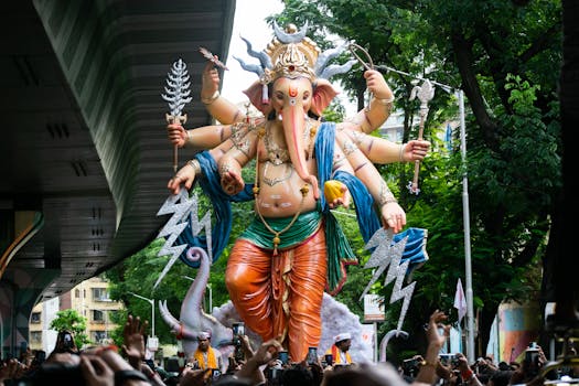 Vibrant Ganesh idol during Ganesh Chaturthi festival street parade in Mumbai, India, surrounded by a lively crowd.