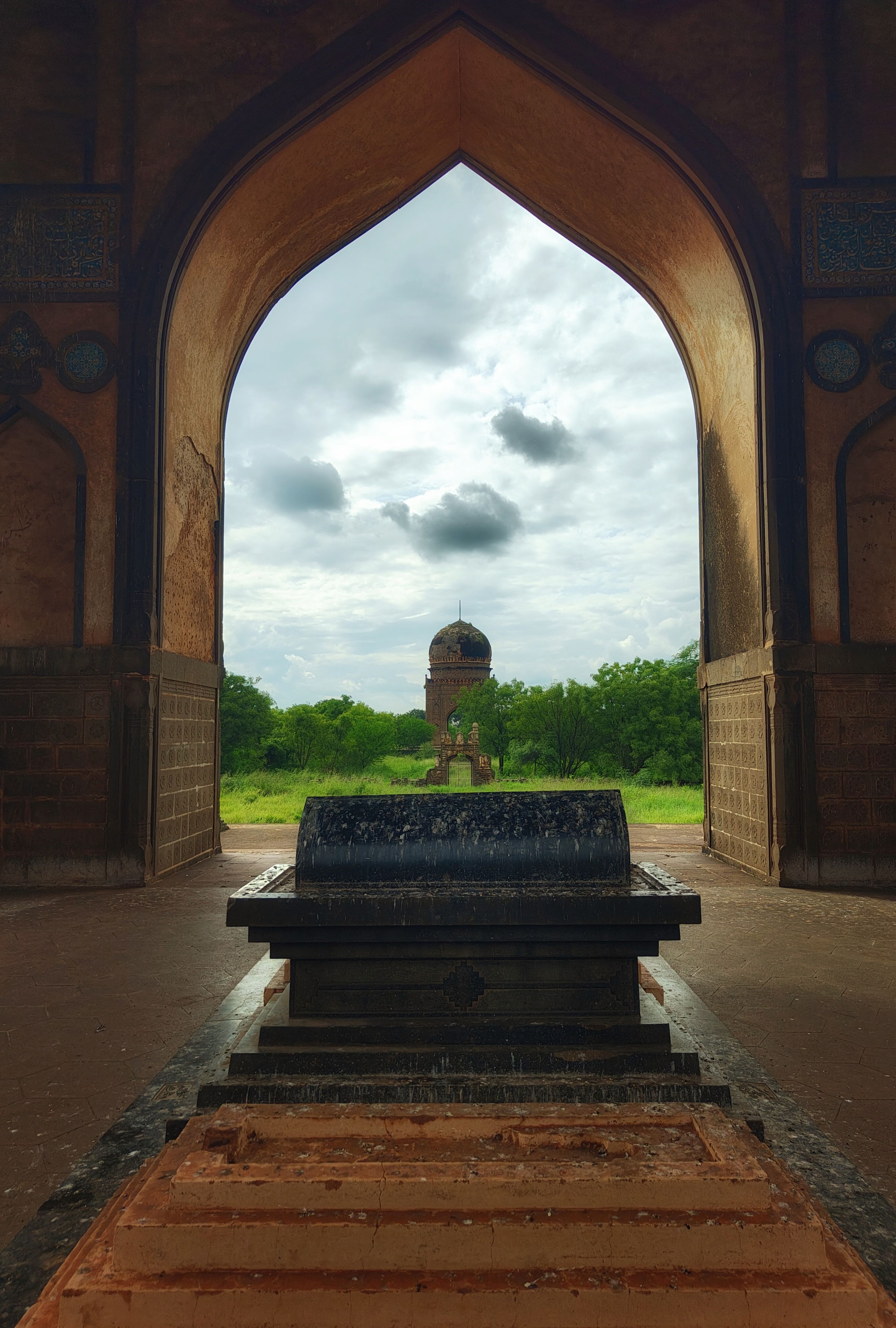 View through a historical archway at Bidar, Karnataka, showcasing rich architecture and lush greenery.
