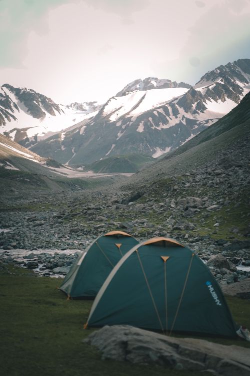 Free Tents nestled in a snowy mountain valley offer a serene winter camping experience. Stock Photo