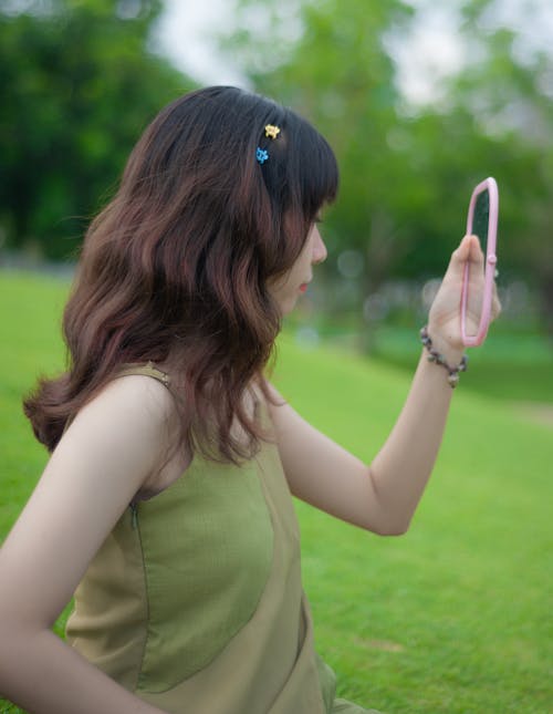 Woman in Green Dress Looking at Hand Mirror