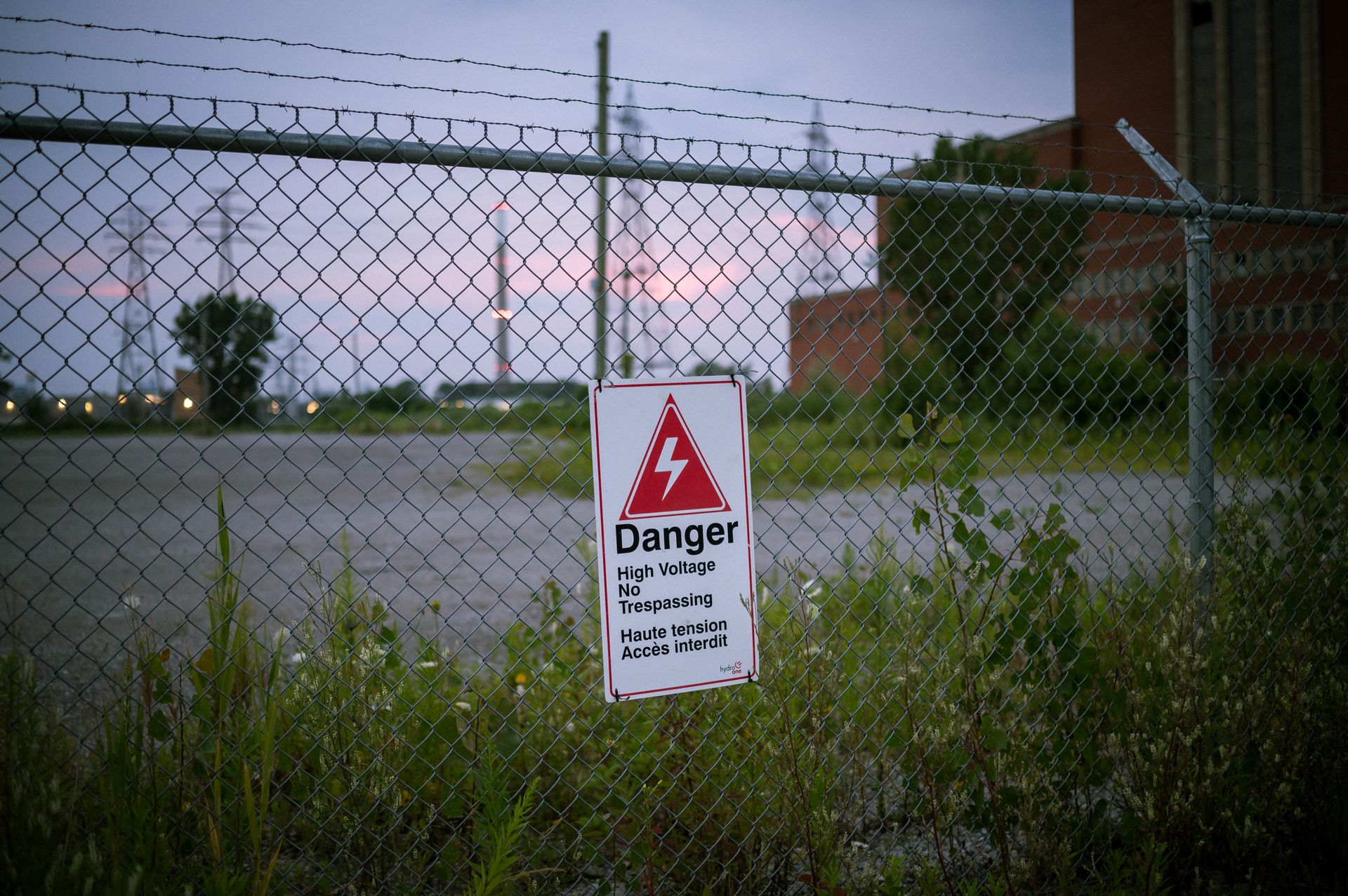 A sign warning of danger is posted in front of a fence