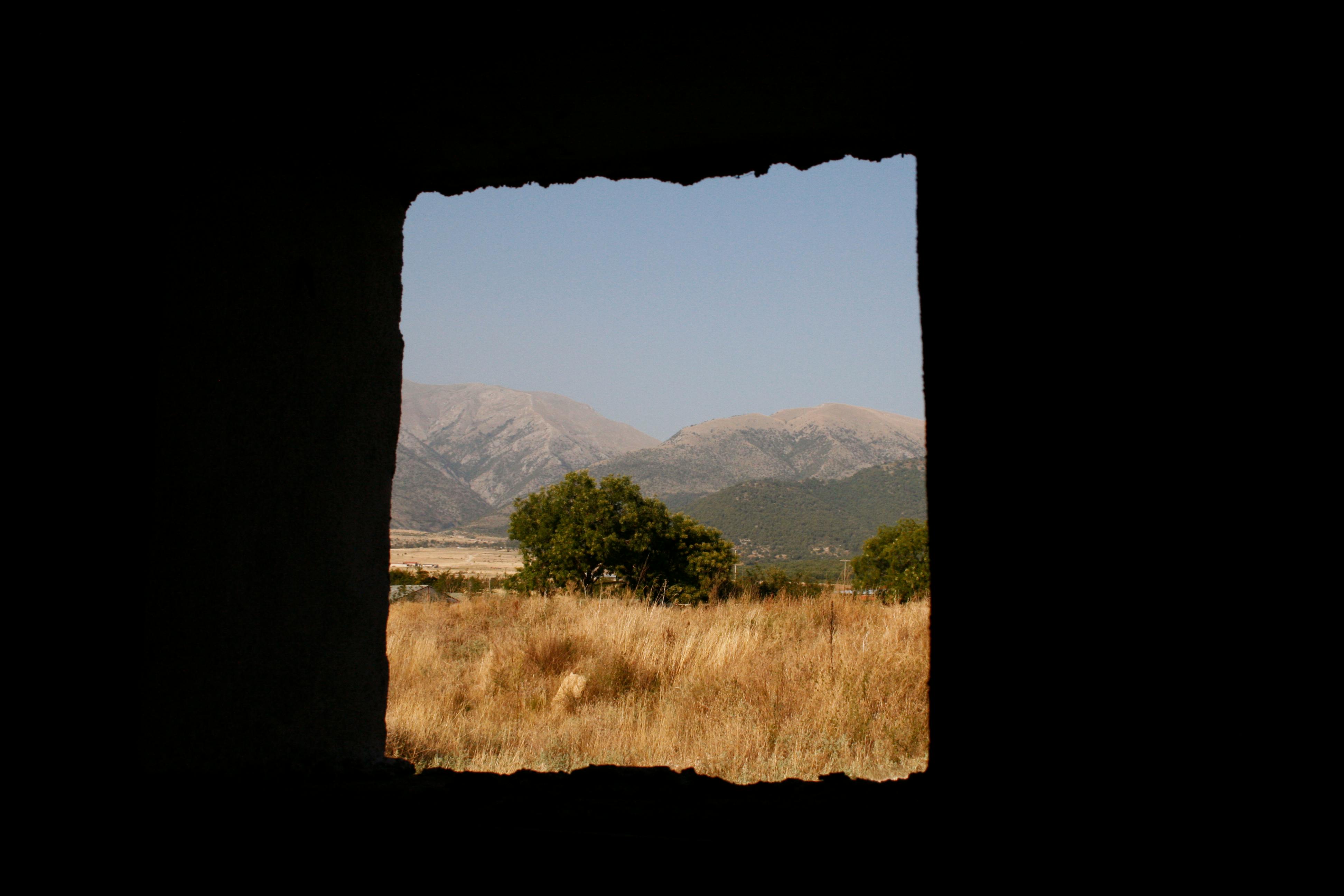 Serene countryside view of Serres, Greece seen through a window frame.