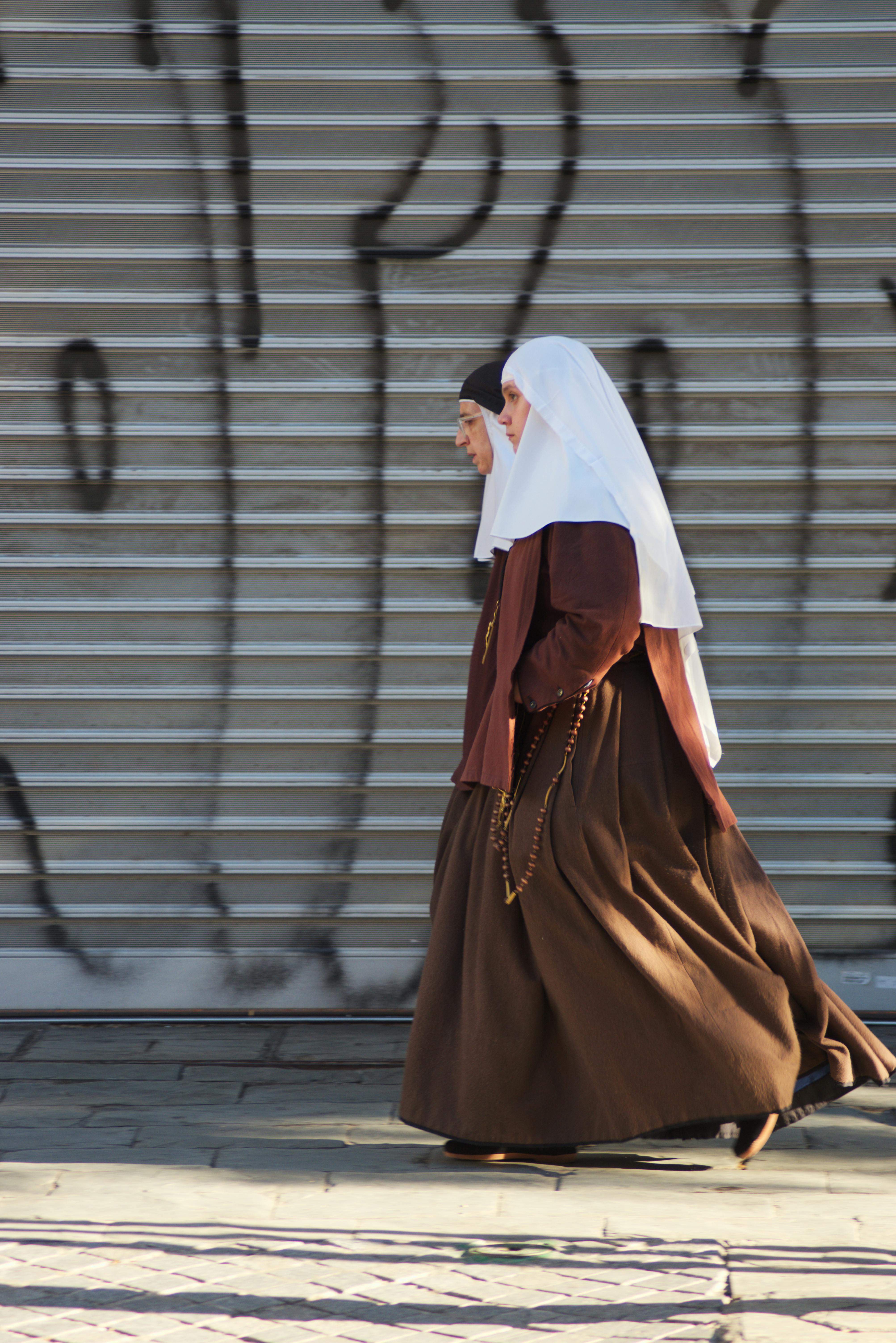 nuns walking near wall