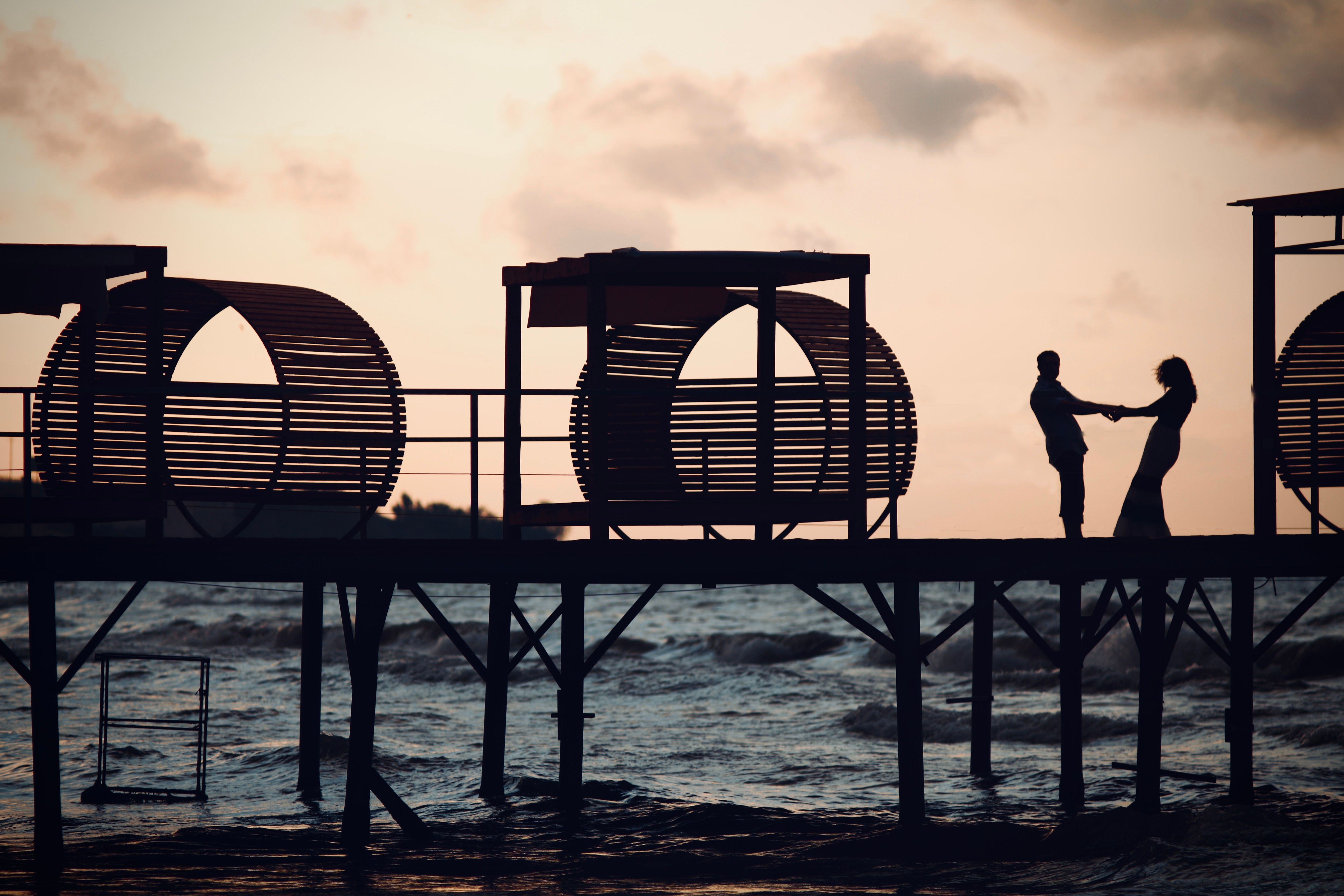 6 Days Private Safari Tour - A couple holding hands in silhouette on a pier in Baku at sunset.