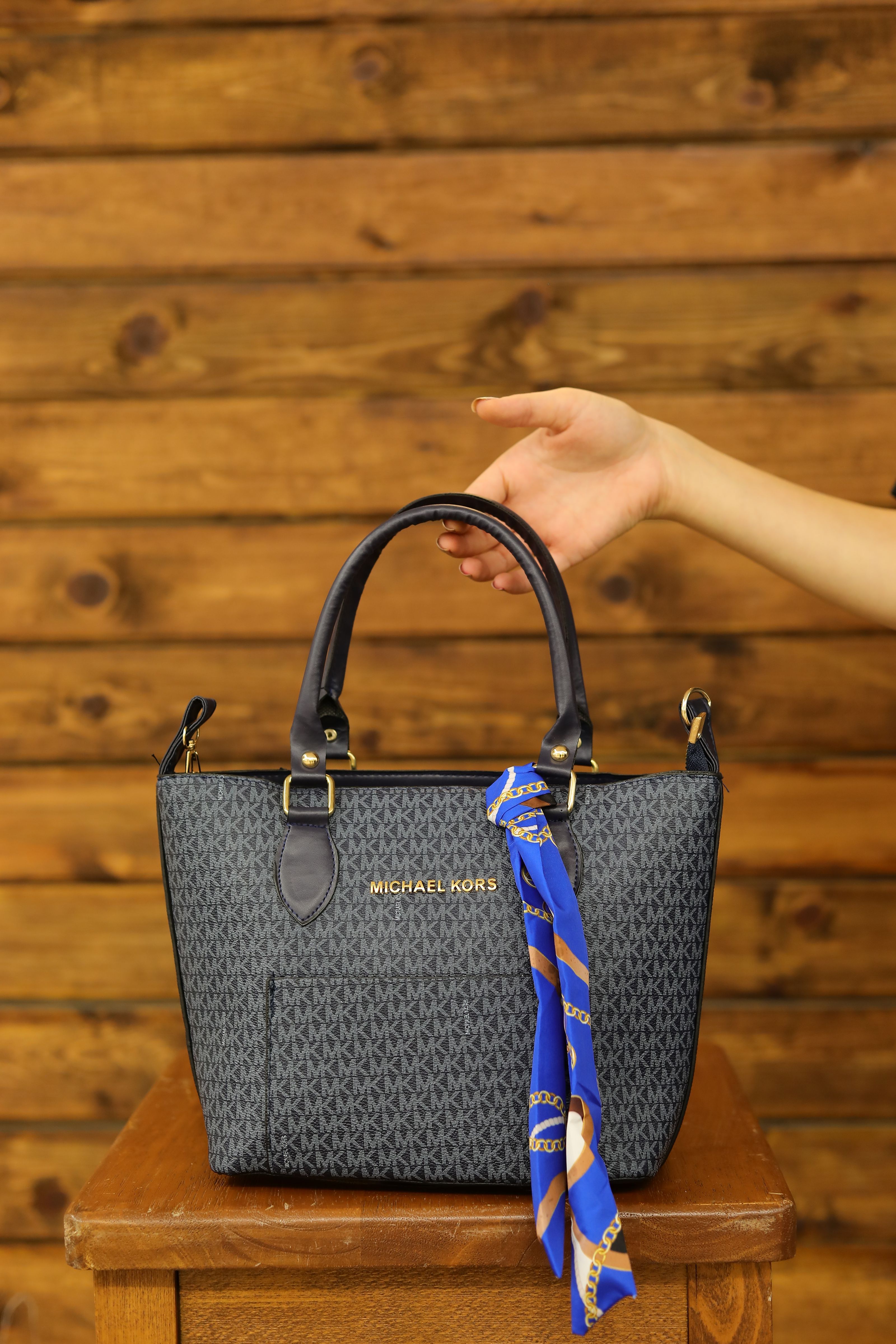 Bolsa de couro escura e elegante com um lenço azul vibrante, contra um fundo de madeira.