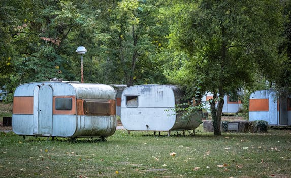 Abandoned vintage caravans in a peaceful forest campsite, ideal for creative travel concepts.