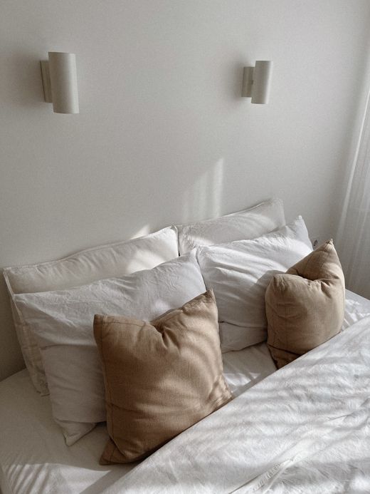 Bedroom with linen pillows in white and clay tones — photo by Aljona Ovtsinnikova on Pexels