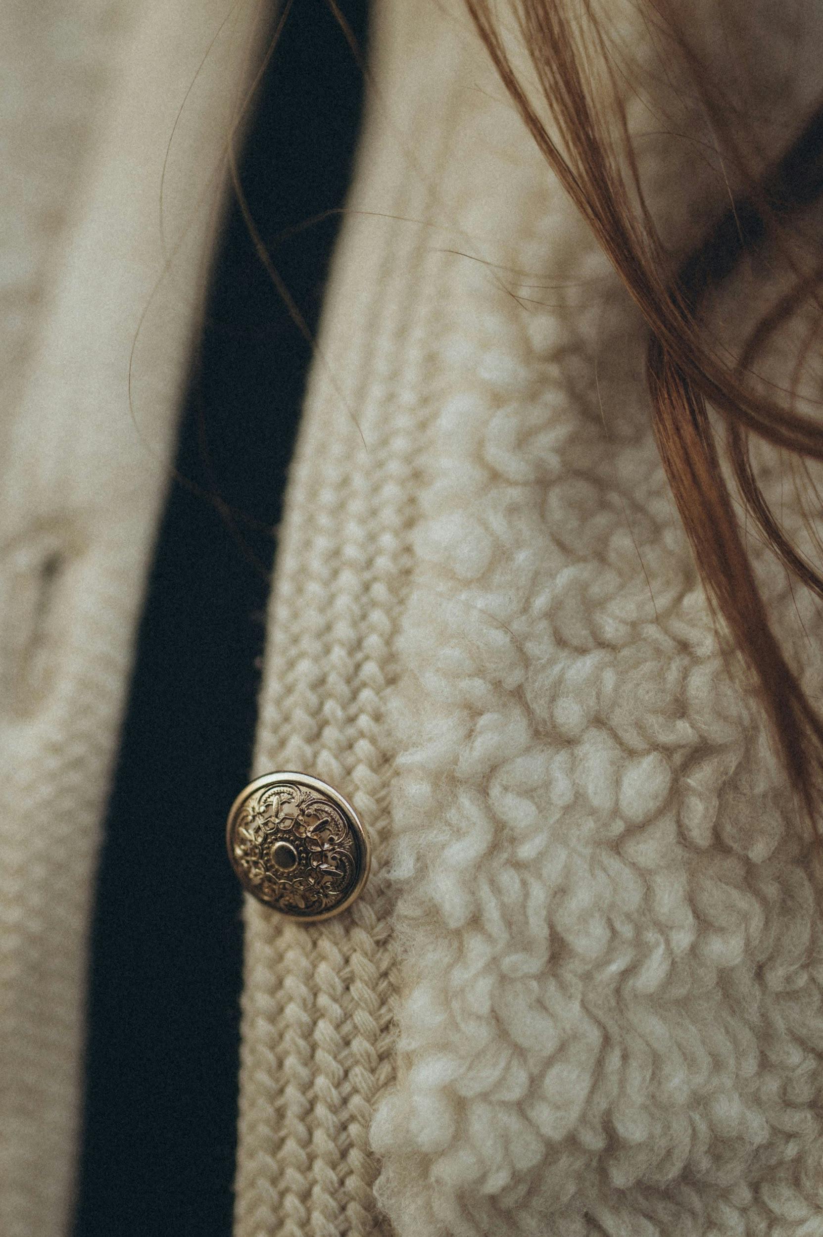 Detailed close-up of a stylish sweater with a decorative button and textured wool fabric.