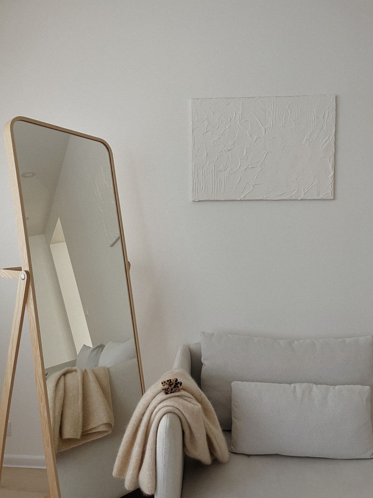 Floor mirror leaning beside a sofa in a bright room