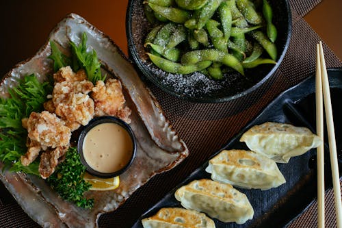 Dumplings on Black Plate Beside Green Beans and Fried Food