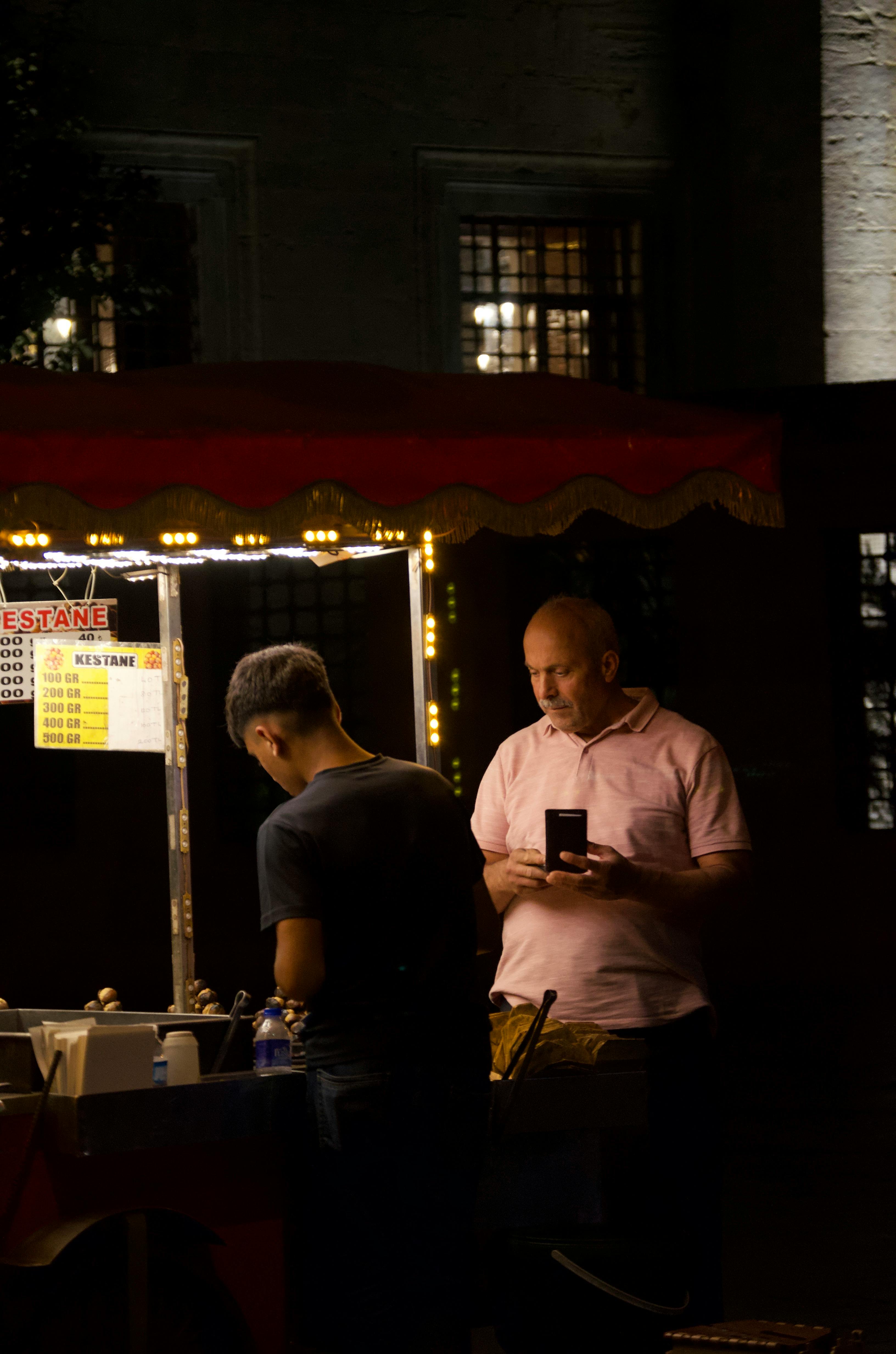 man selling food in the city street at dusk