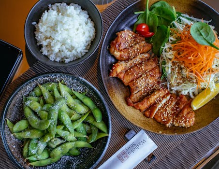 一顿精美的日本餐，有照烧鸡、米饭、沙拉和毛豆