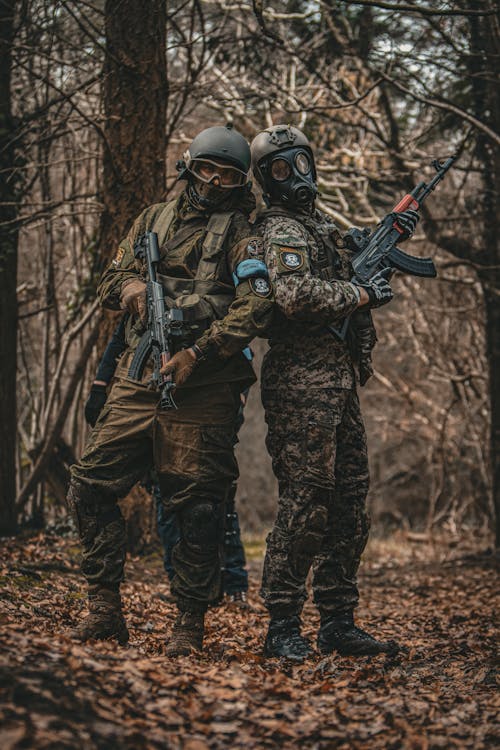 People in Uniforms and with Machine Guns in Forest