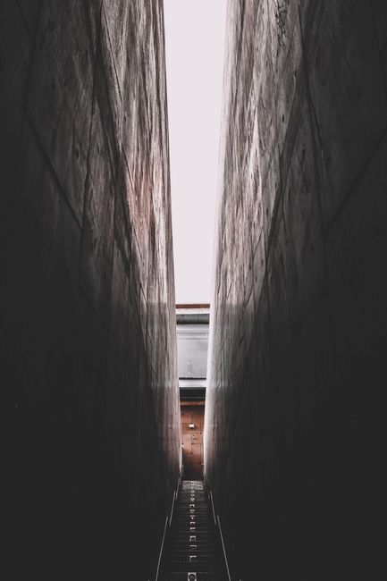 A dramatic shot of a narrow passageway with stairs between towering walls.