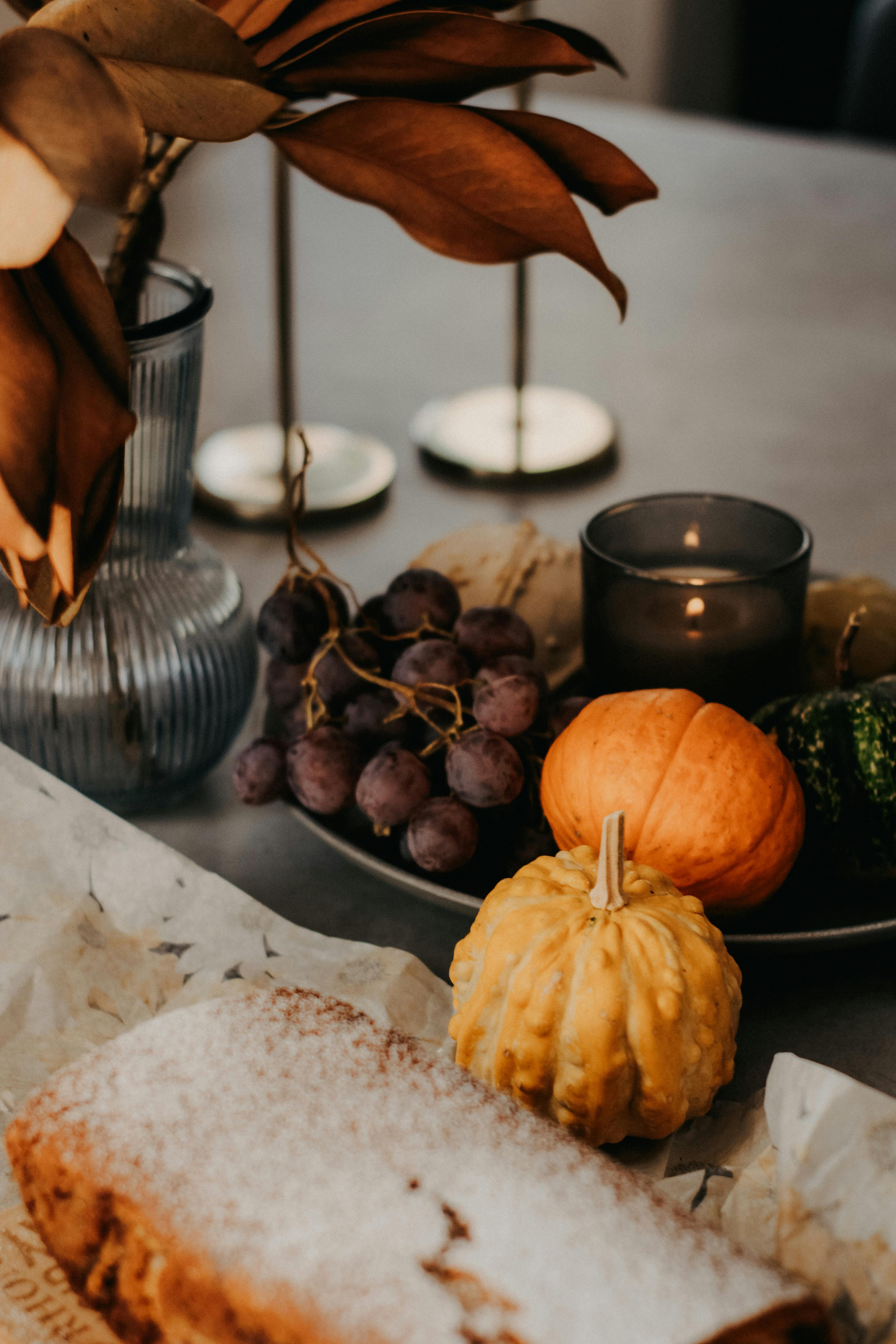 Cozy fall still life with gourds, grapes, and a pastry capturing the essence of autumn.