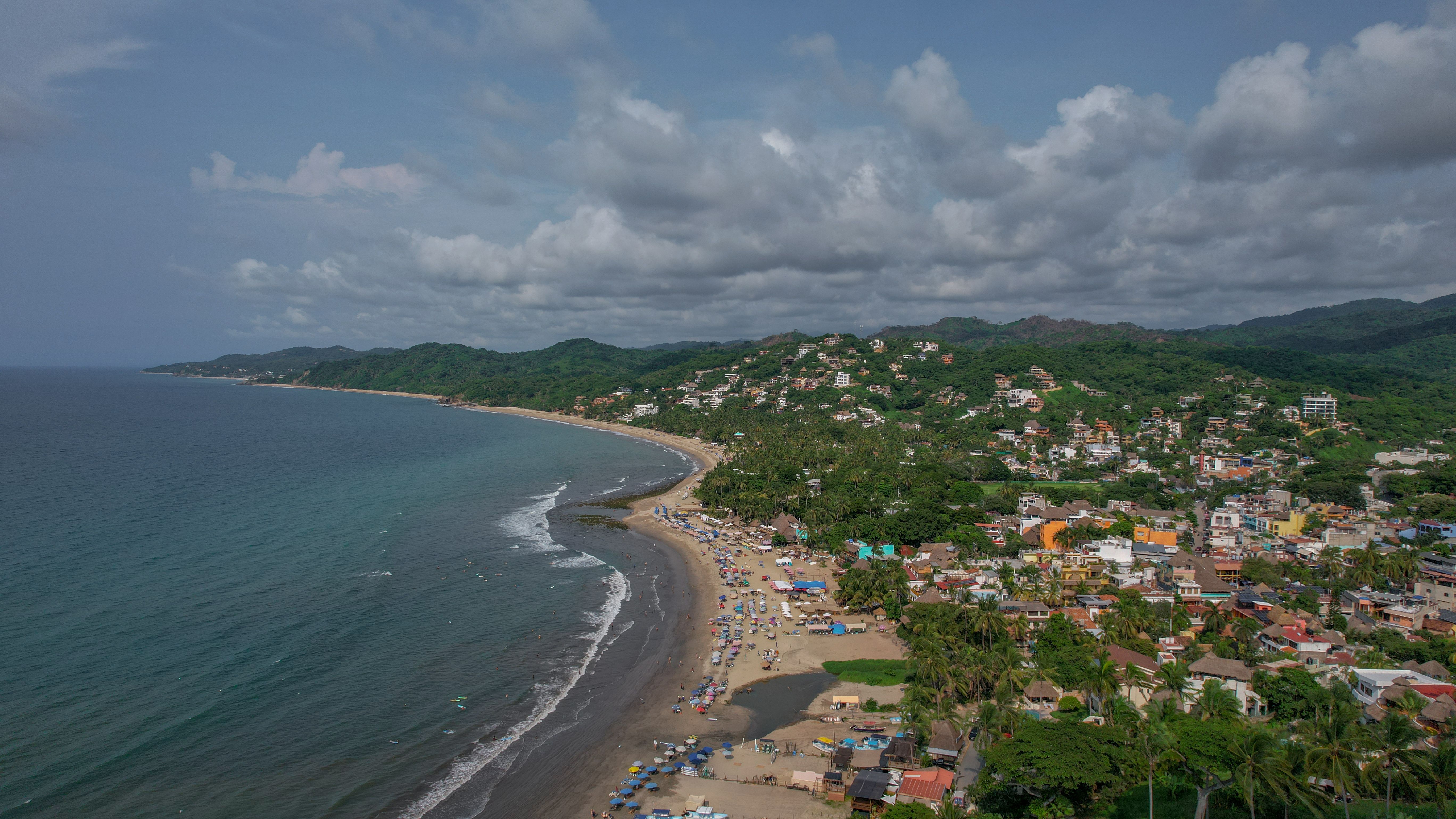 Aerial view of Sayulita beach and town against green hills, the end of the drive from Puerto Vallarta airport to Sayulita