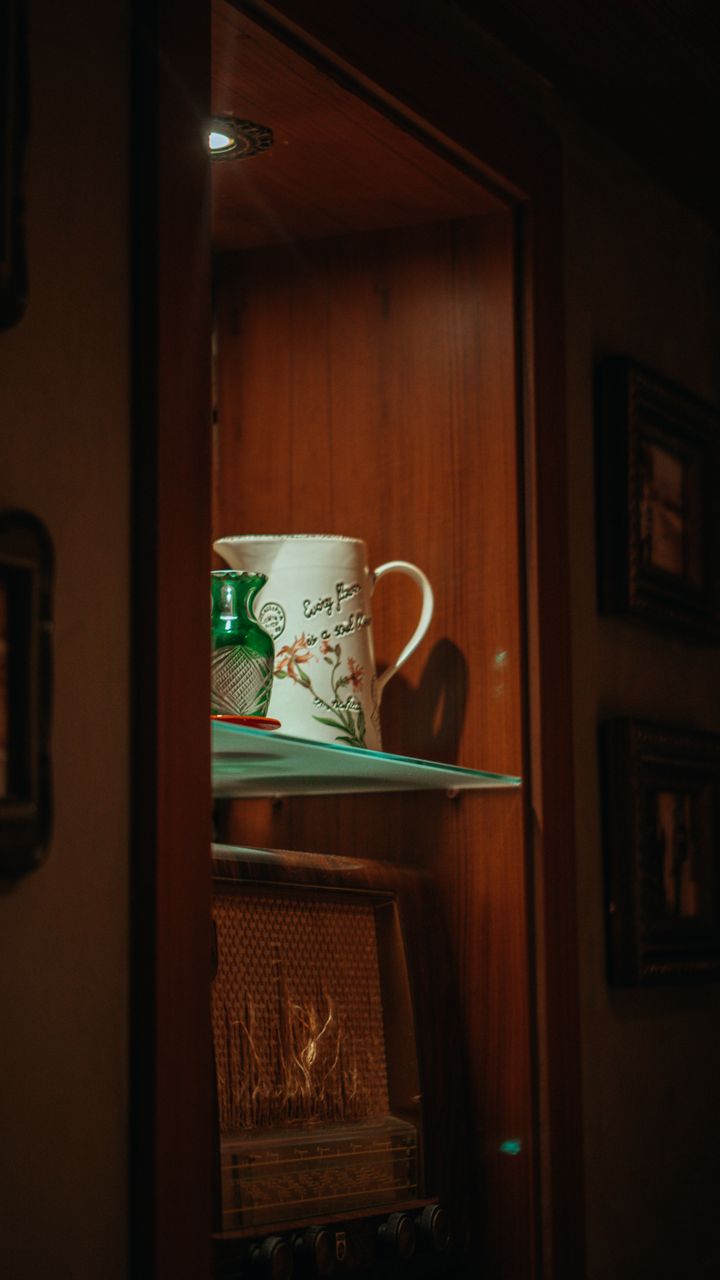 A cozy kitchen LED lit coffee cabinet display with warm lights highlighting mugs and coffee beans
