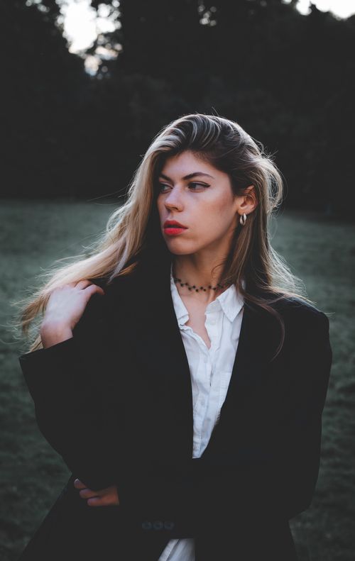 Free Portrait of a fashionable woman in a blazer and blouse outdoors, exuding confidence. Stock Photo