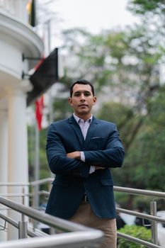 A confident man in a blazer poses outdoors, exuding professionalism and elegance.