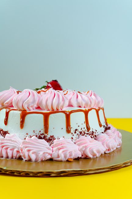 Close-up of a pink cream cake with strawberries and caramel drizzle, perfect for dessert lovers.