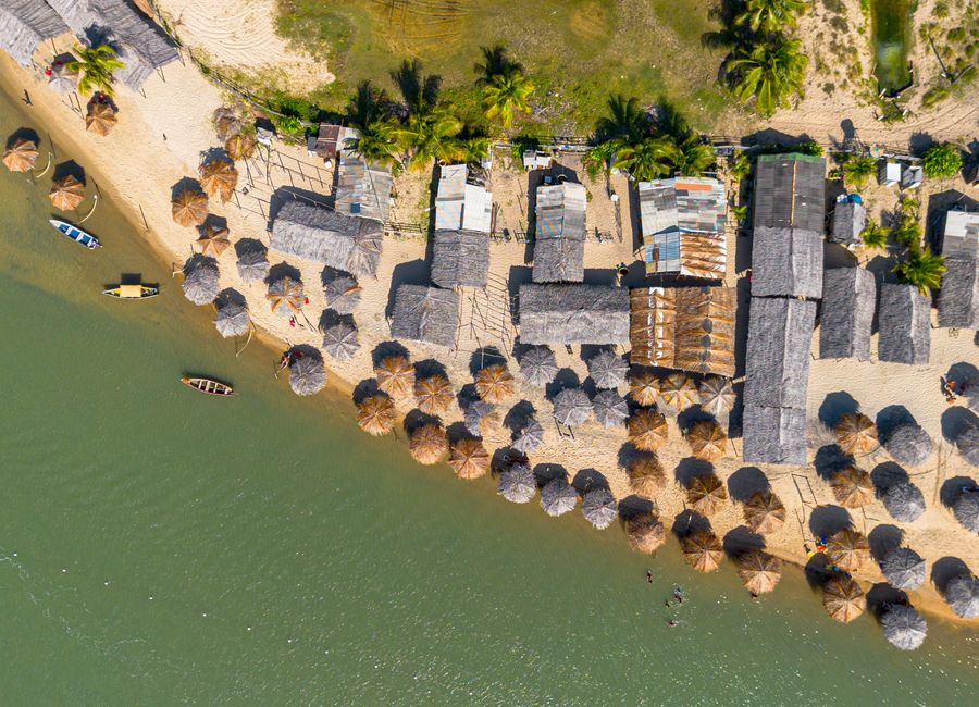 Stunning aerial view of a tropical beach resort in Conde, Brazil, with umbrellas and boats along the coastline.