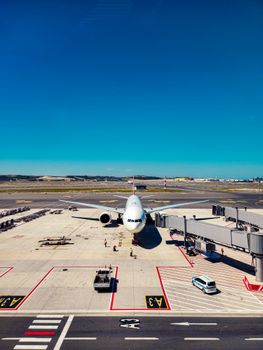 Airplane parked at airport gate, ready for passenger boarding under clear blue skies.