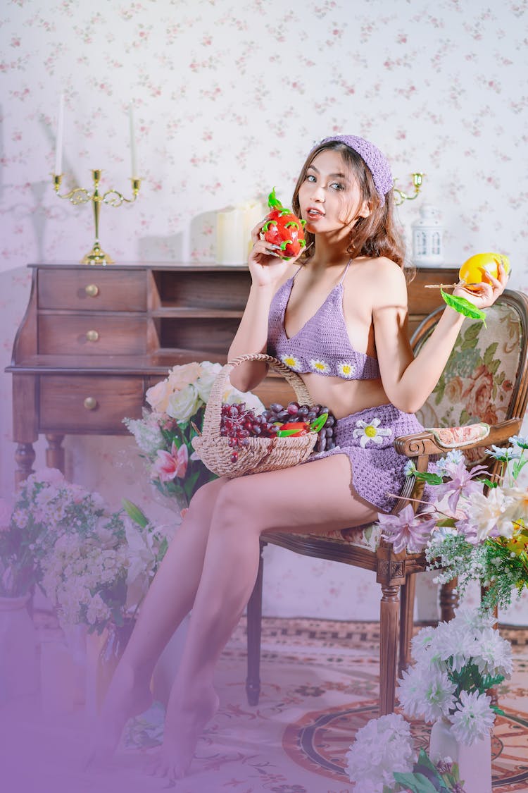 Woman In Bra Sitting On Armchair And Posing With Flowers And Fruit