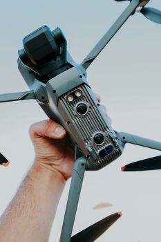 Close-up of a hand holding a sophisticated drone with cameras, outdoors.