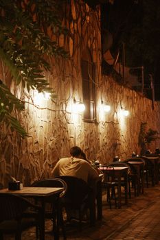 A couple enjoys a cozy night at an outdoor restaurant in İzmir, Türkiye, with ambient lights.