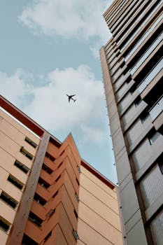 在摩天大楼的景色中，一架飞机在蓝天下飞行