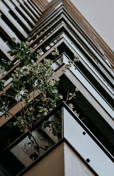 低角度镜头下的现代摩天大楼，与绿色植物形成城市绿化的对比