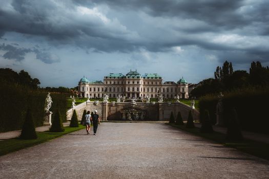 View of the majestic Belvedere Palace in Vienna under dramatic clouds, emphasizing classic architecture.