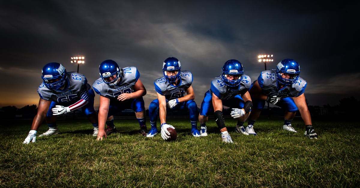 Football Players in Blue Jersey Lined Under Grey White Cloudy Sky during Sunset