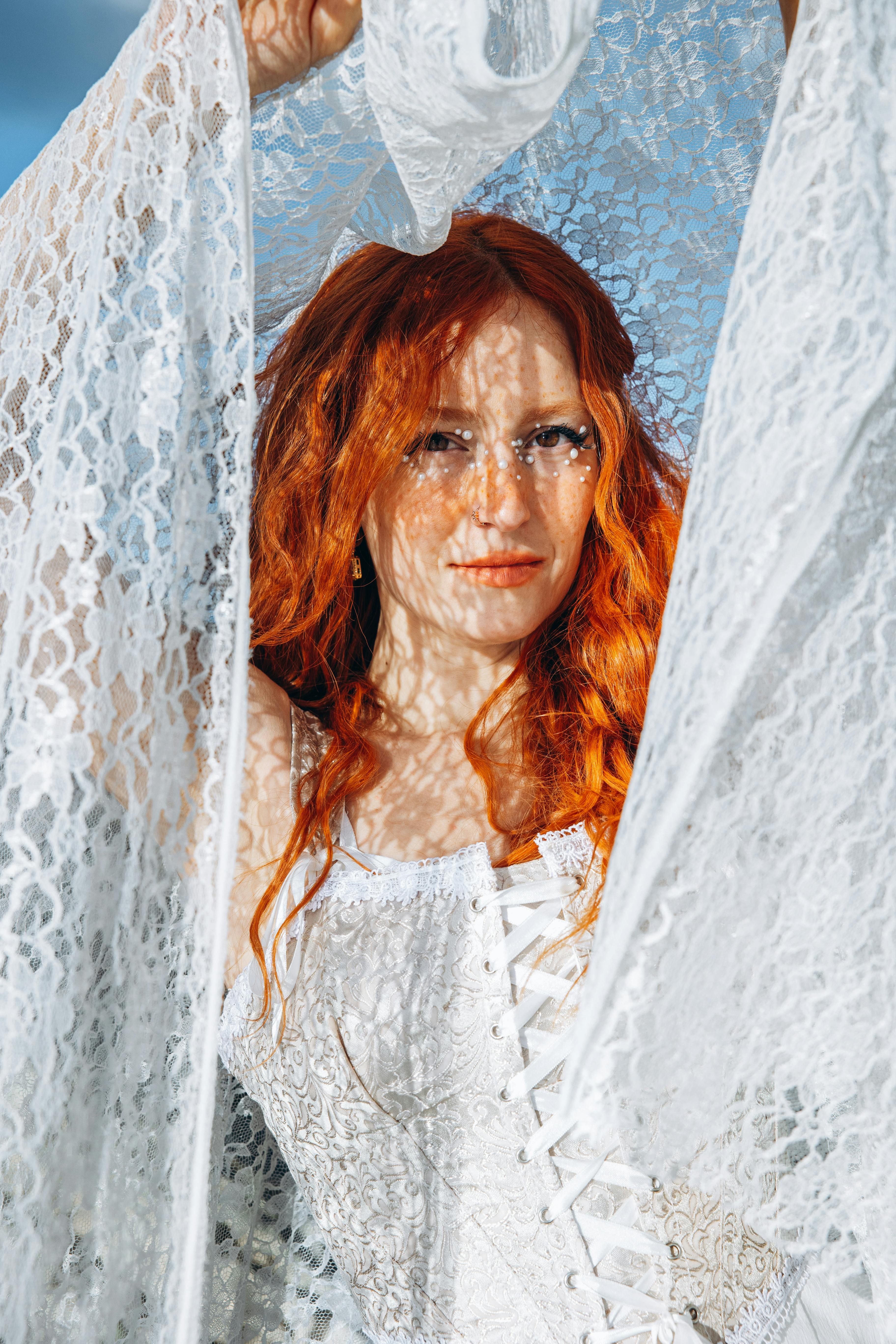 a woman with red hair and white lace dress