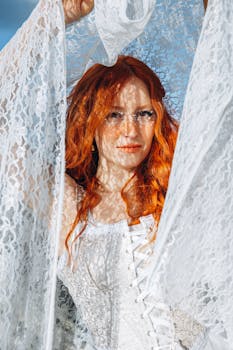 Red-haired woman posing outdoors with lace, vibrant and artistic portrait.