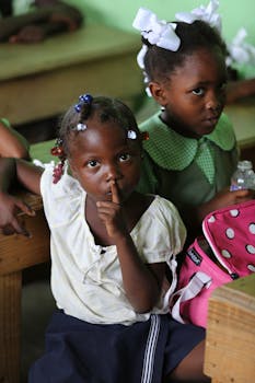Two young girls sitting in a classroom, engaging attentively.
