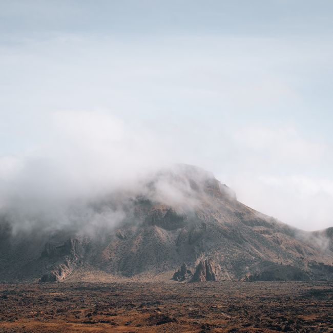 Serene view of a misty mountain surrounded by barren land, capturing natural beauty.