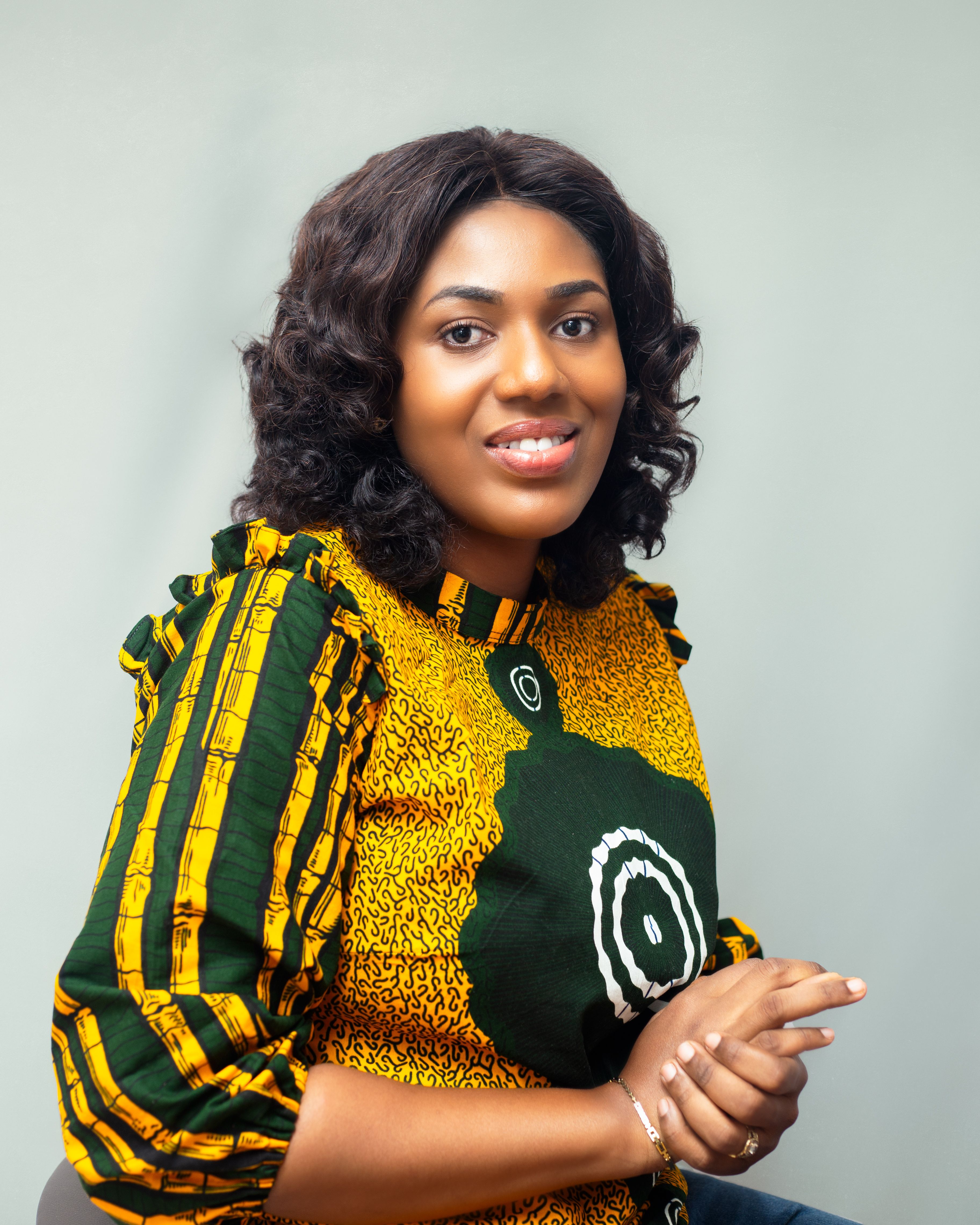 A smiling woman poses in traditional African attire during a studio shoot in Kumasi, Ghana.