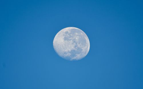 Free Capture of a bright daytime moon set against a clear blue sky, showcasing lunar detail. Stock Photo
